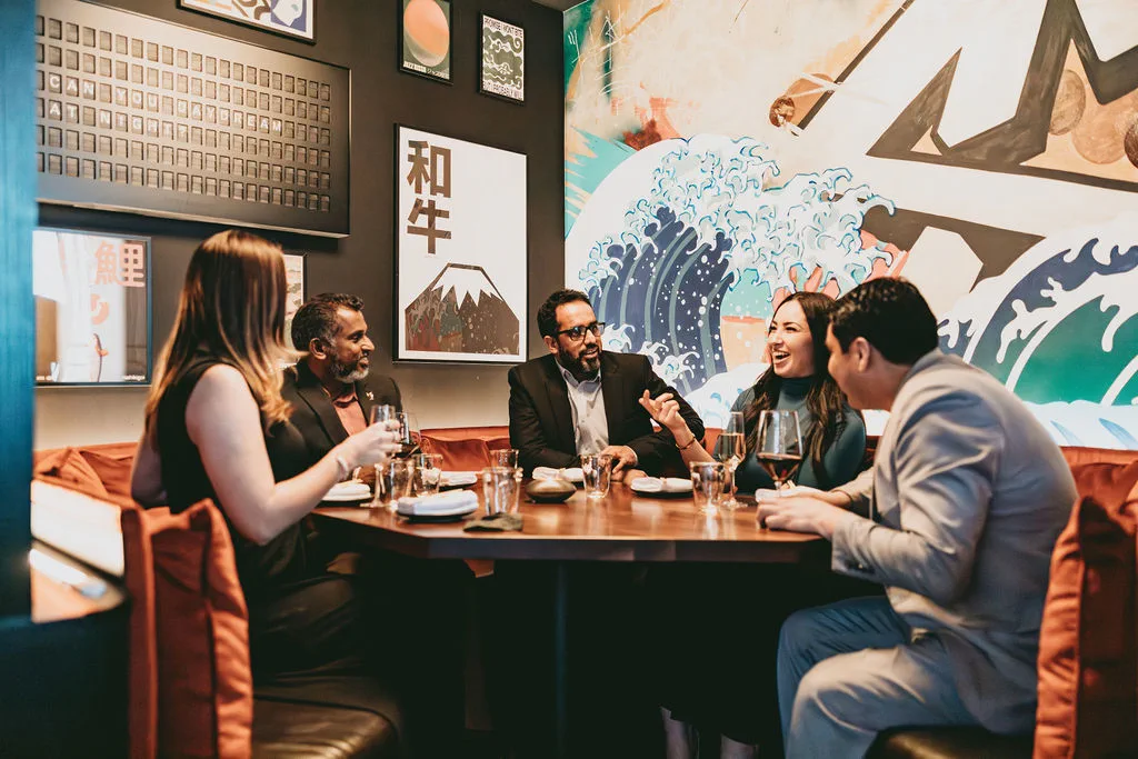 Friends gathered beneath the wave mural at The Naisho Room